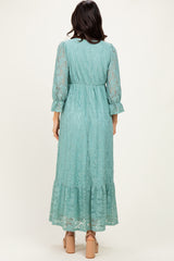 woman wearing a long teal lace dress with 3/4 sleeves and a ruffled hem, viewed from the back