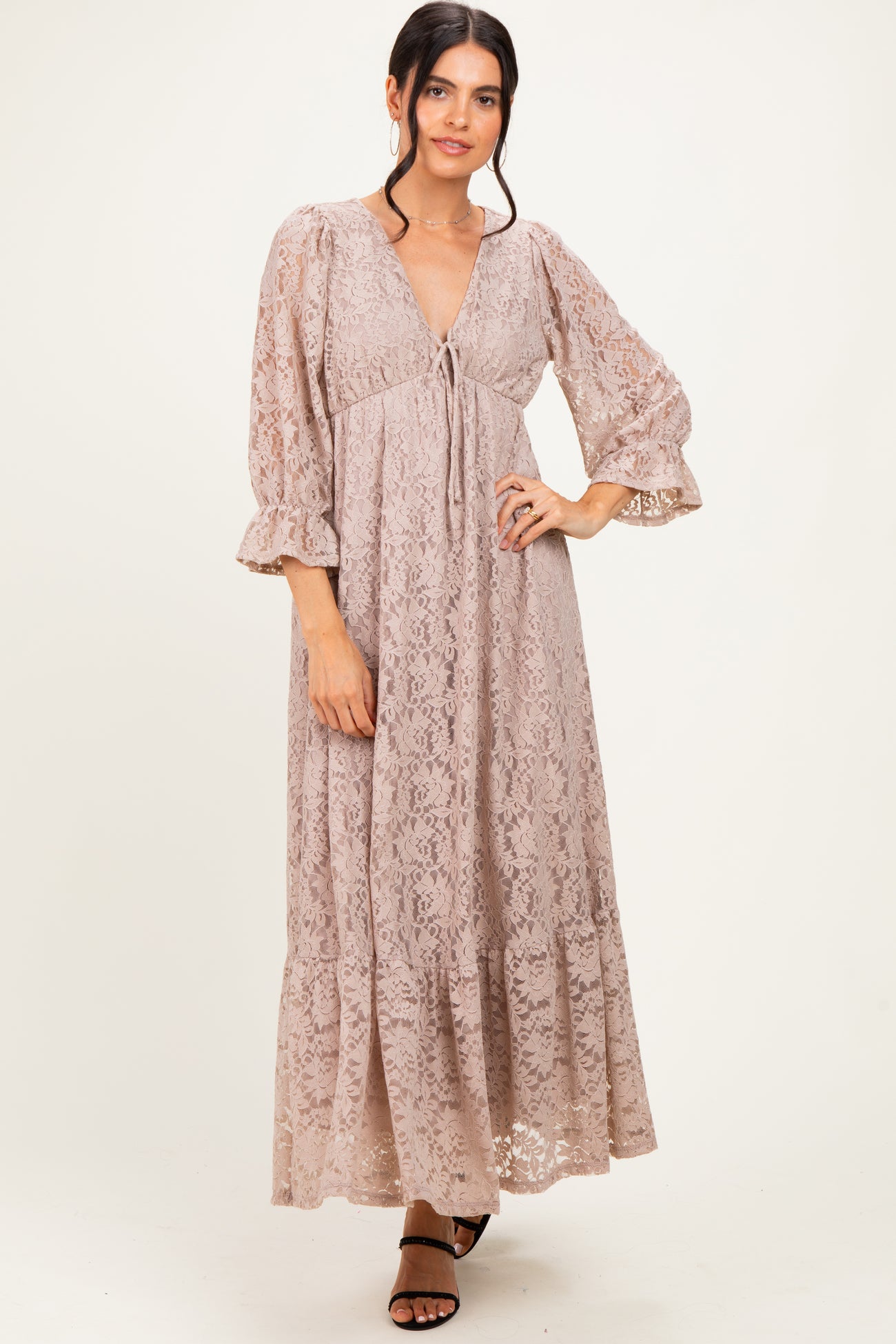 woman wearing a blush lace maxi dress with bell sleeves and a cinched empire waist