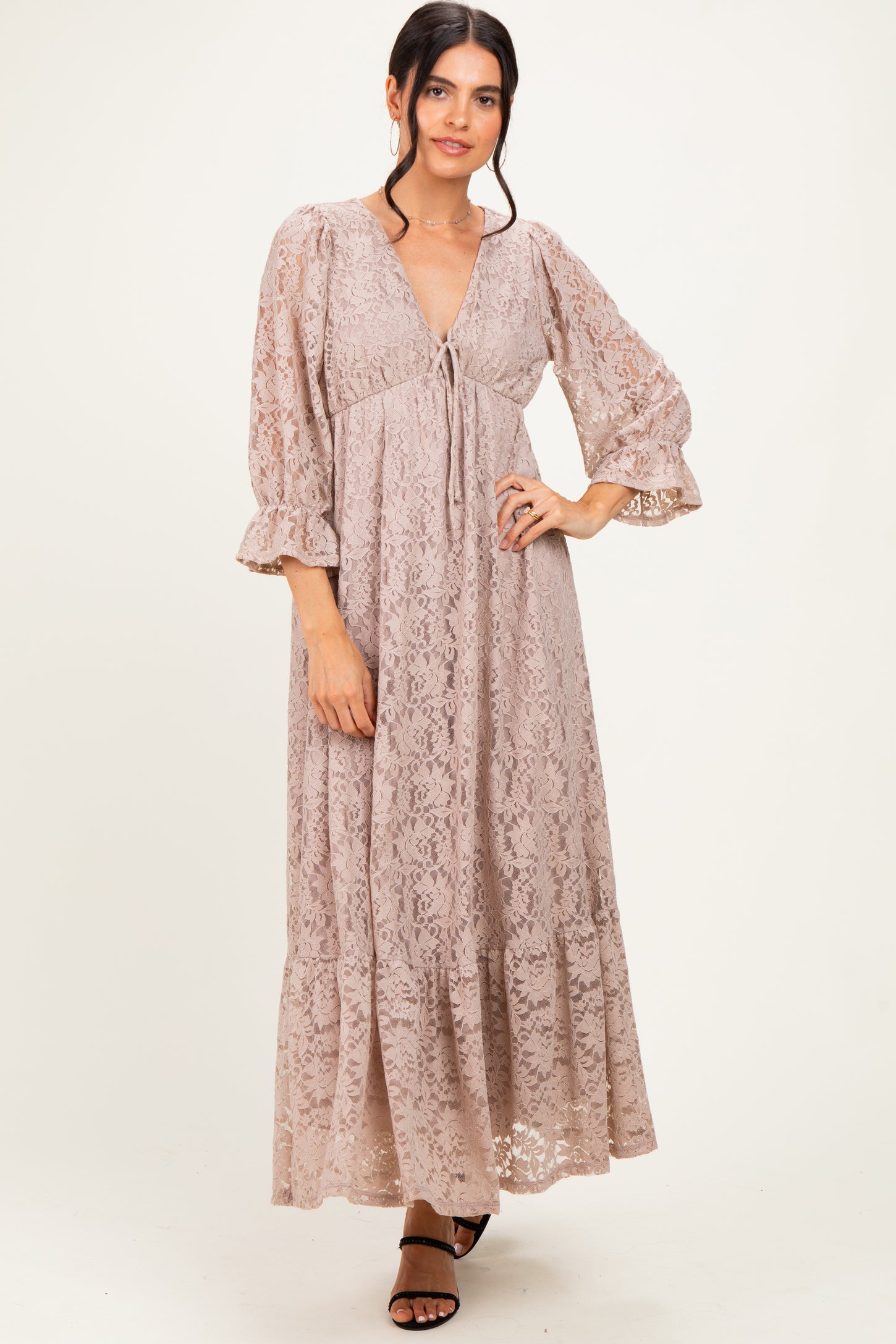 woman wearing a blush lace maxi dress with bell sleeves and a cinched empire waist
