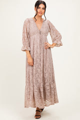 woman wearing a blush lace maxi dress with bell sleeves and a cinched empire waist
