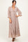 woman wearing a blush lace maxi dress with bell sleeves and a cinched empire waist