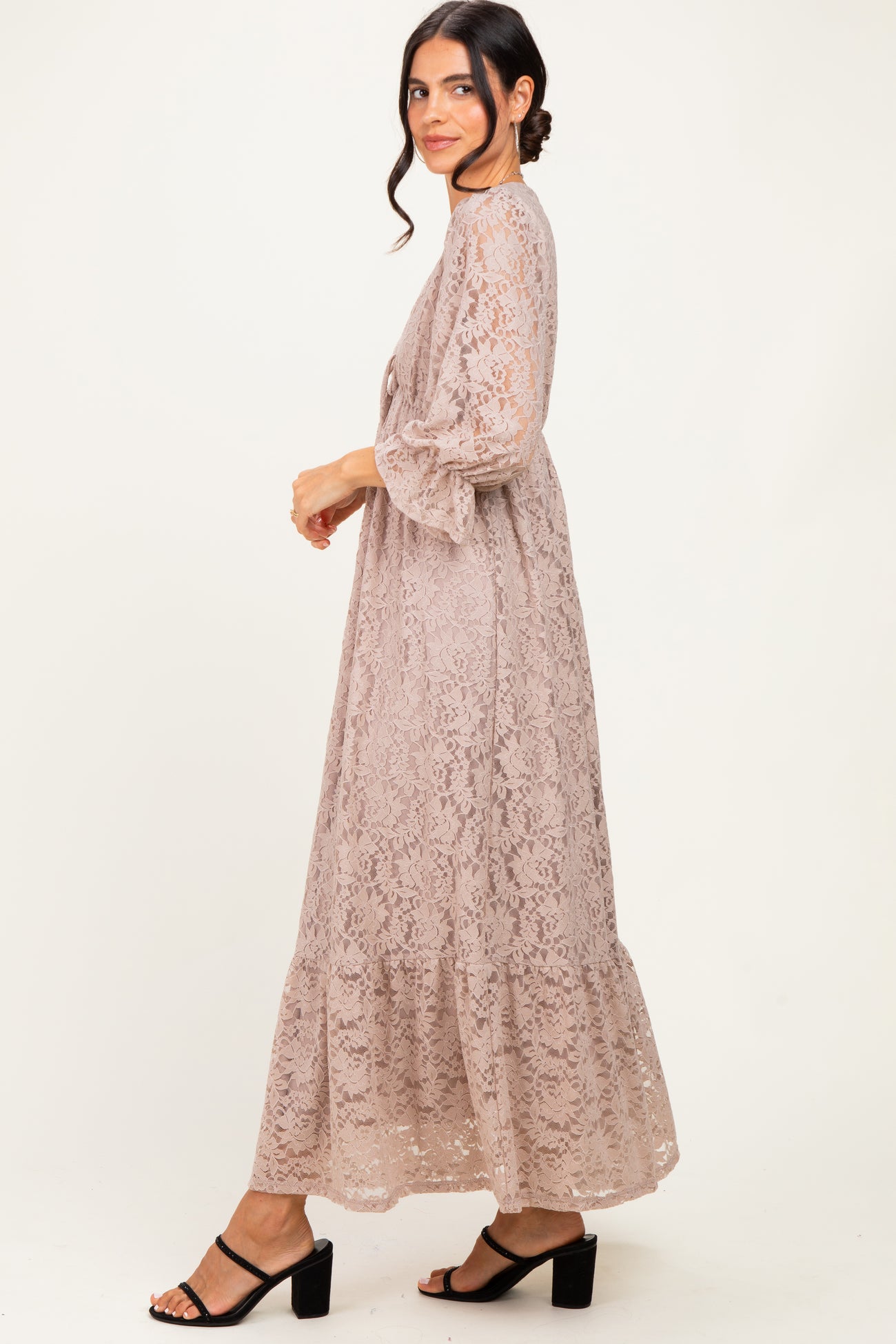 woman wearing a light taupe lace maxi dress with bell sleeves and tiered design, styled with black block heel sandals