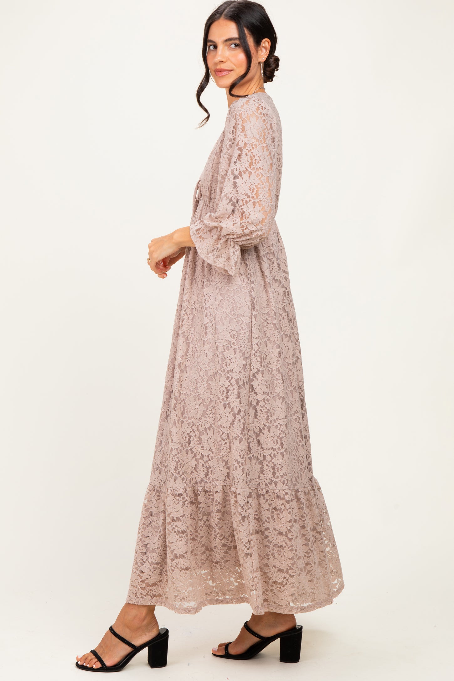 woman wearing a light taupe lace maxi dress with bell sleeves and tiered design, styled with black block heel sandals