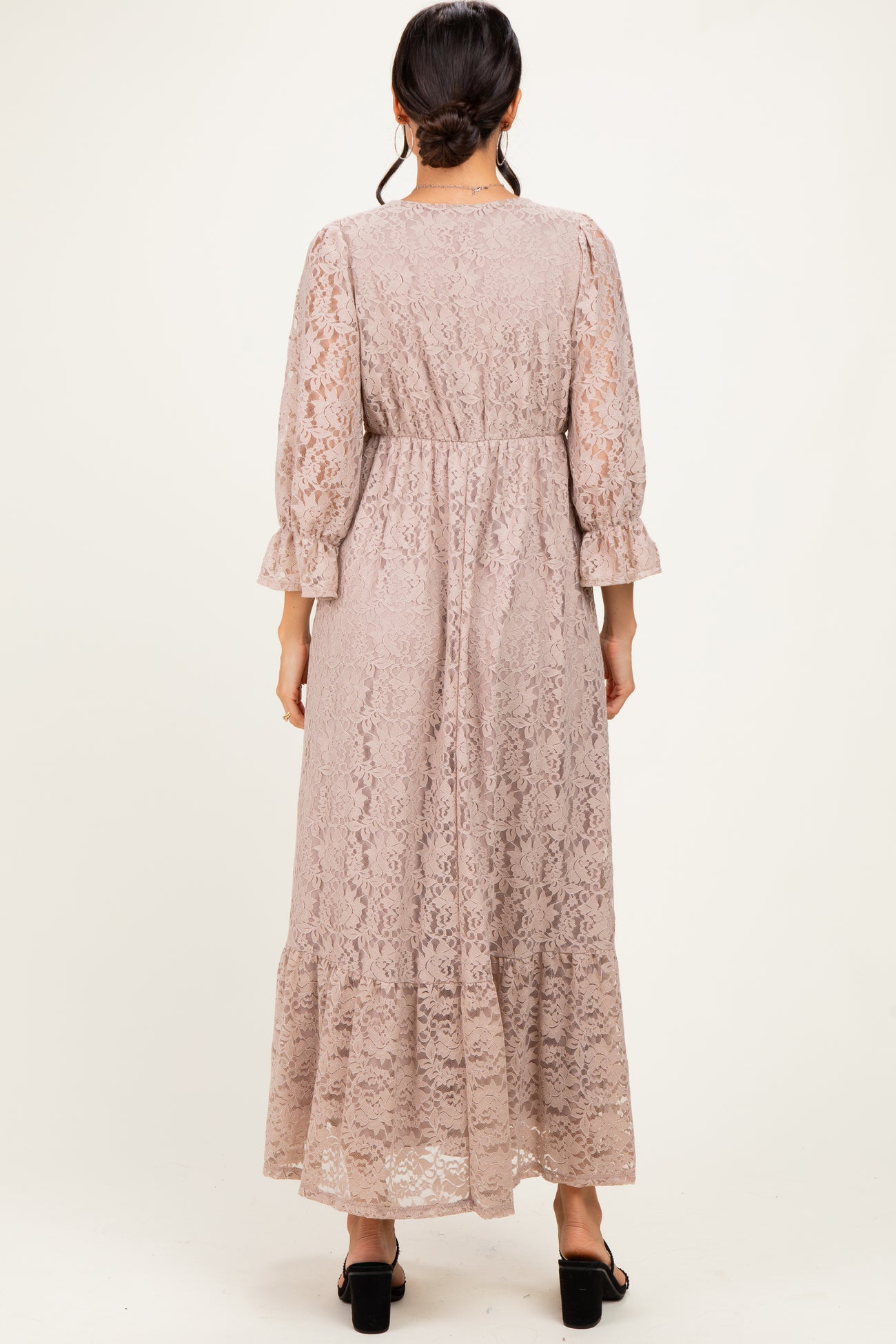 woman wearing a brown lace maxi dress with long sleeves and a ruffled hem, viewed from the back
