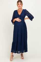 woman wearing a navy blue lace maxi maternity dress and gently holding her baby bump