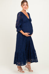 woman wearing a navy blue lace maternity dress with a tie detail and a visible baby bump