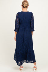 woman wearing a navy blue lace maternity dress with three-quarter sleeves and a flowy skirt, showing a baby bump