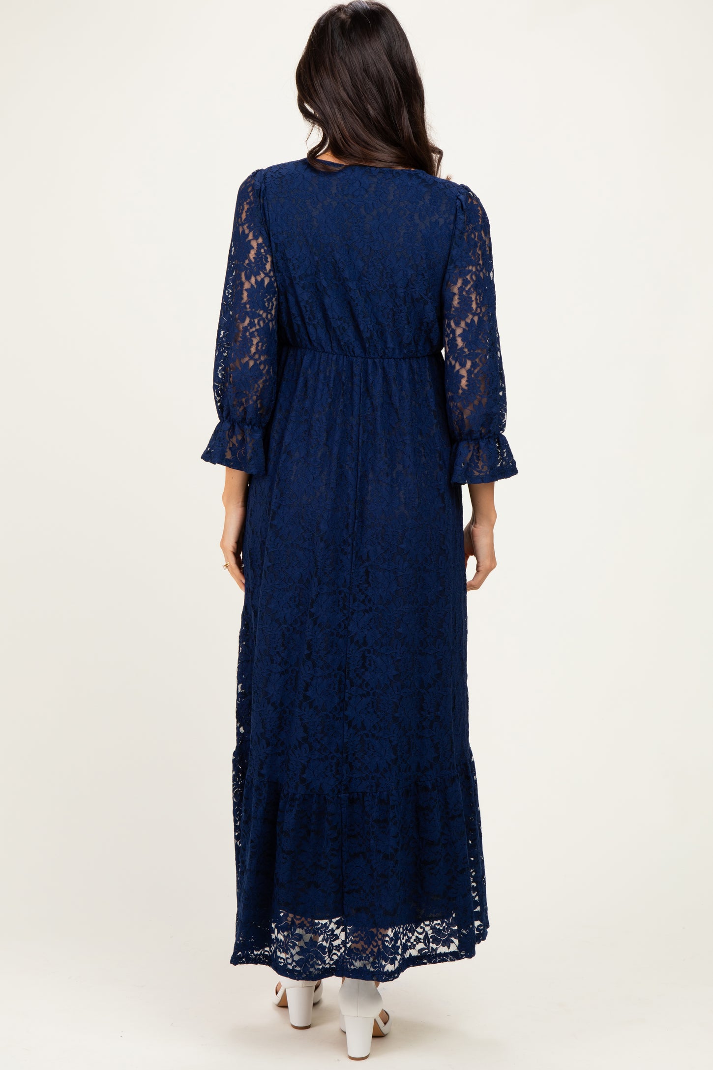 woman wearing a navy blue lace maxi dress with three-quarter sleeves and a tiered hem, viewed from the back