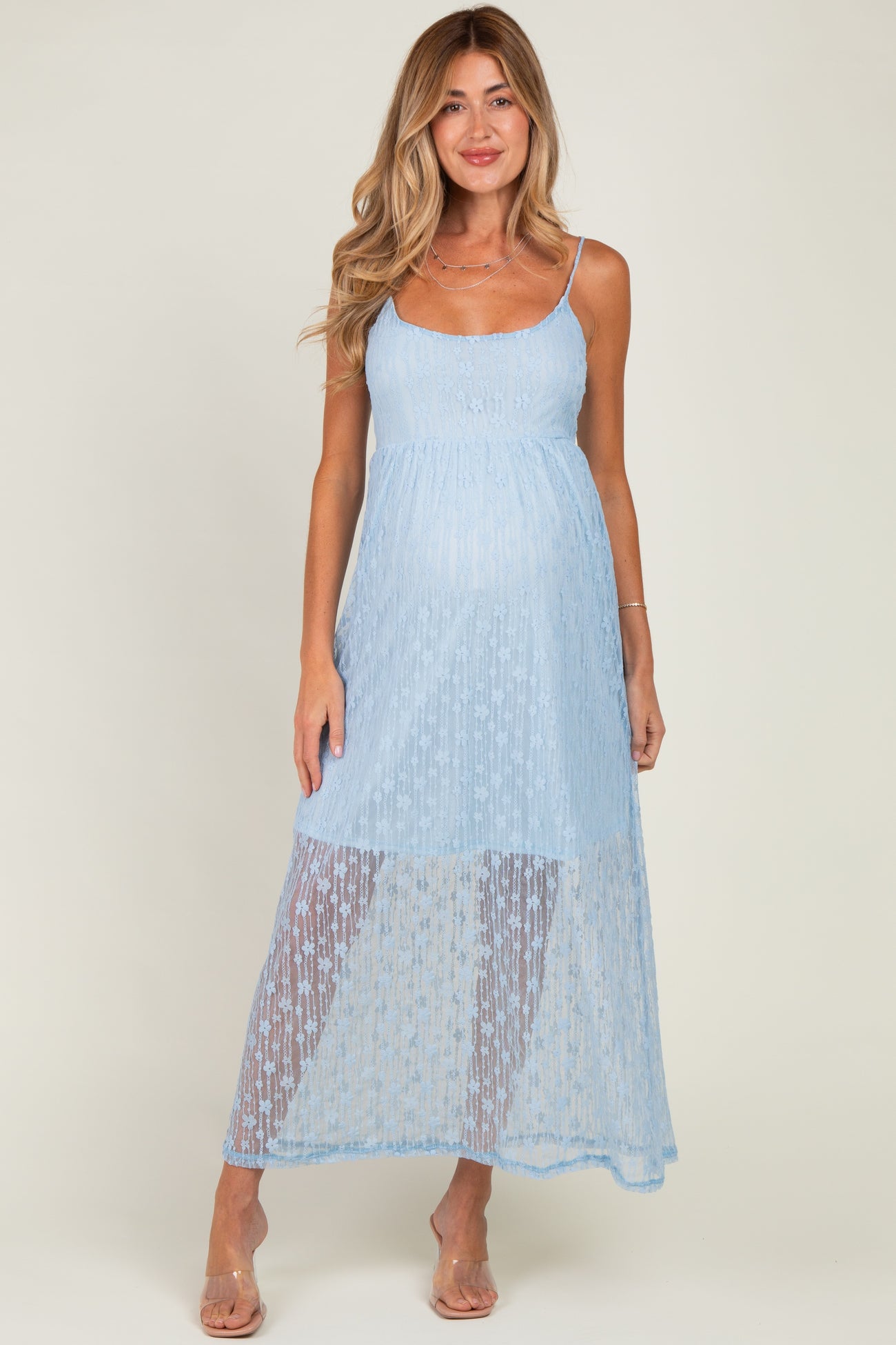 woman wearing a light blue maternity dress with sheer detailing and a flowing skirt, showing her baby bump
