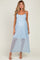 woman wearing a light blue maternity dress with sheer detailing and a flowing skirt, showing her baby bump
