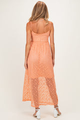 woman wearing a sheer orange maternity maxi dress with adjustable straps and a flowy silhouette
