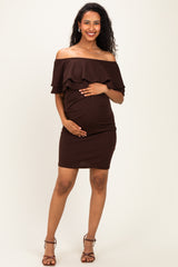 woman wearing a brown off-the-shoulder maternity dress with ruffle detail and holding her baby bump