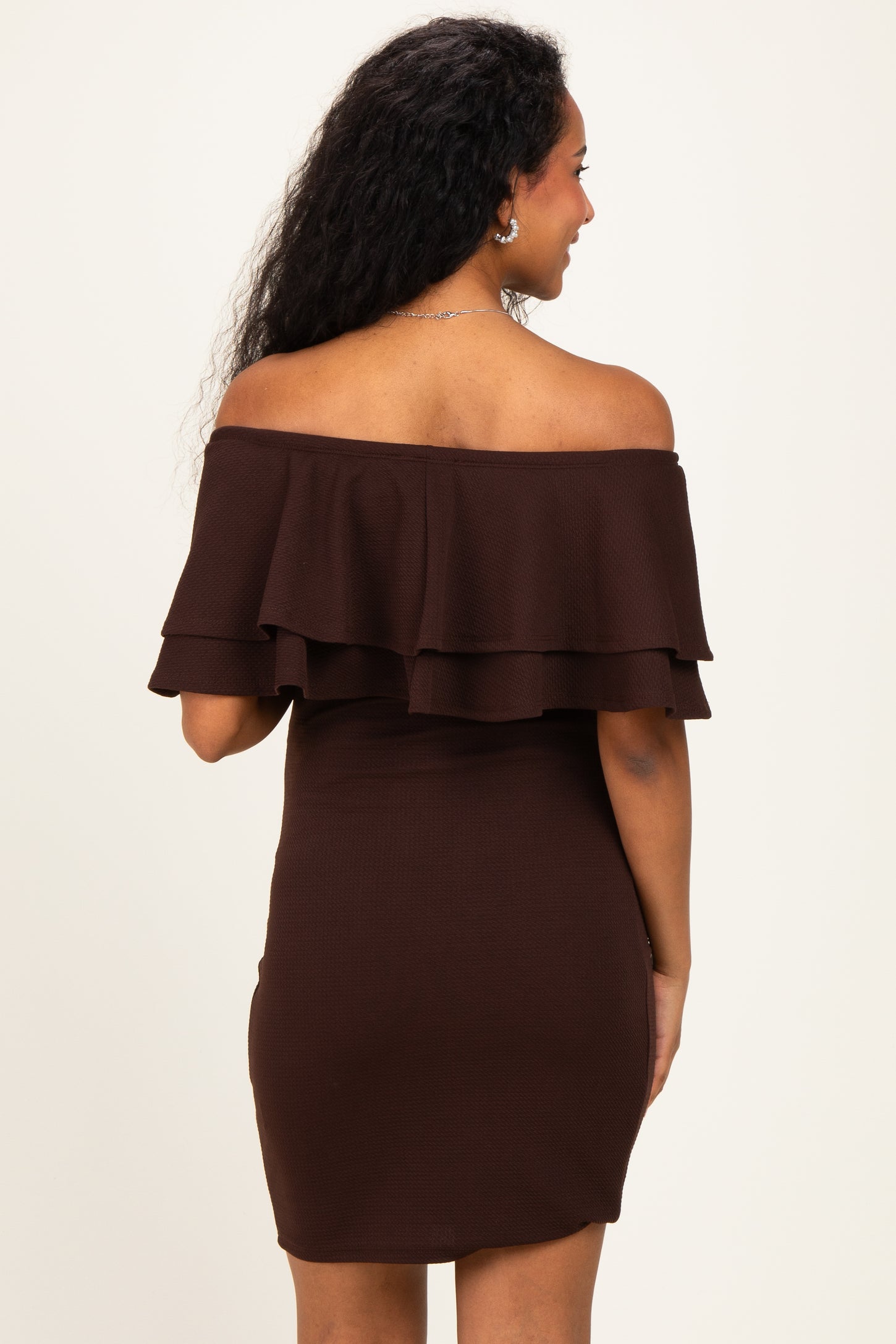 woman wearing a dark brown off-the-shoulder maternity dress with ruffle details and a fitted silhouette