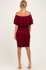 woman wearing a burgundy off-the-shoulder maternity dress with layered ruffles and a fitted silhouette