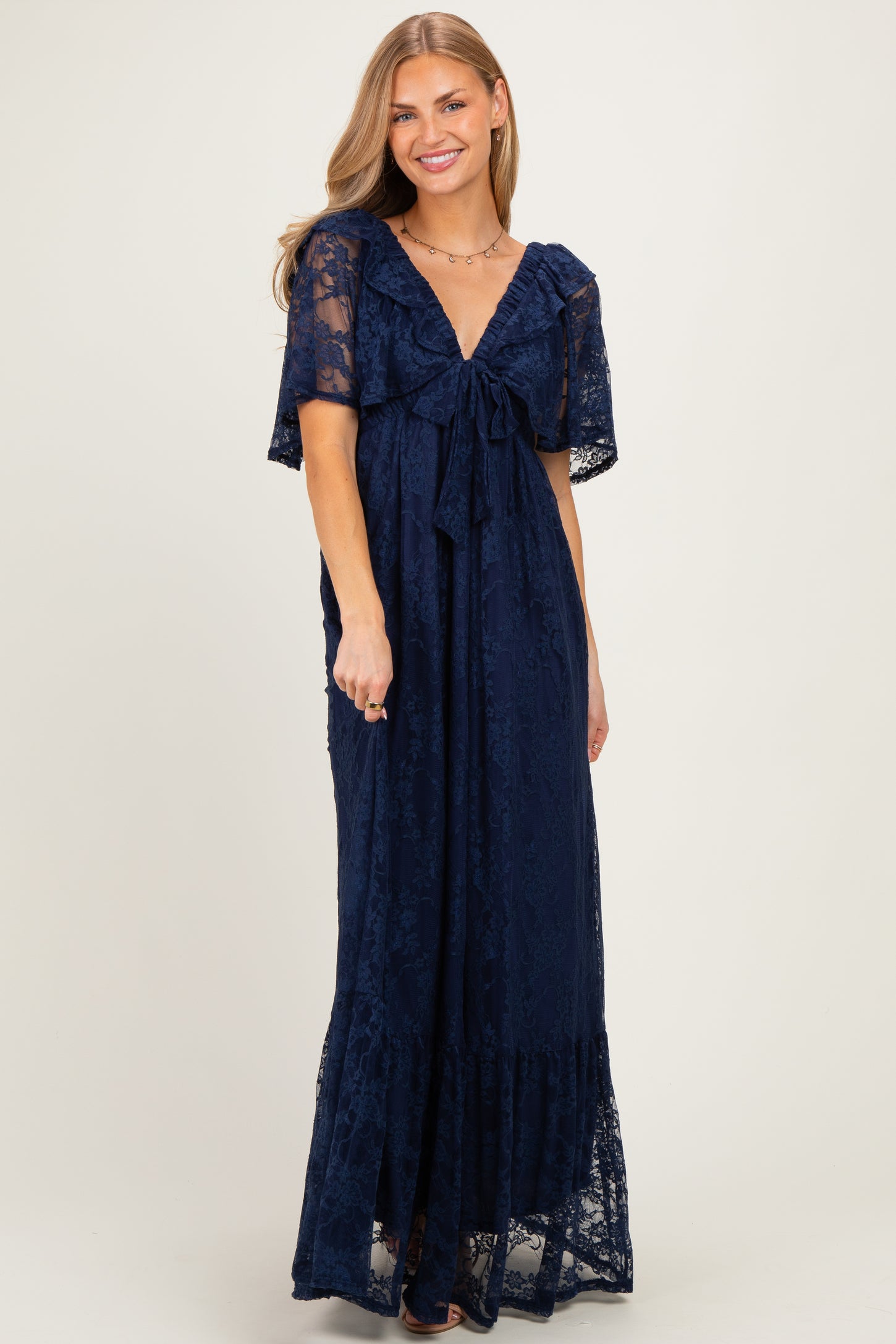 woman wearing a navy blue lace maxi dress with a tie front and short sheer sleeves