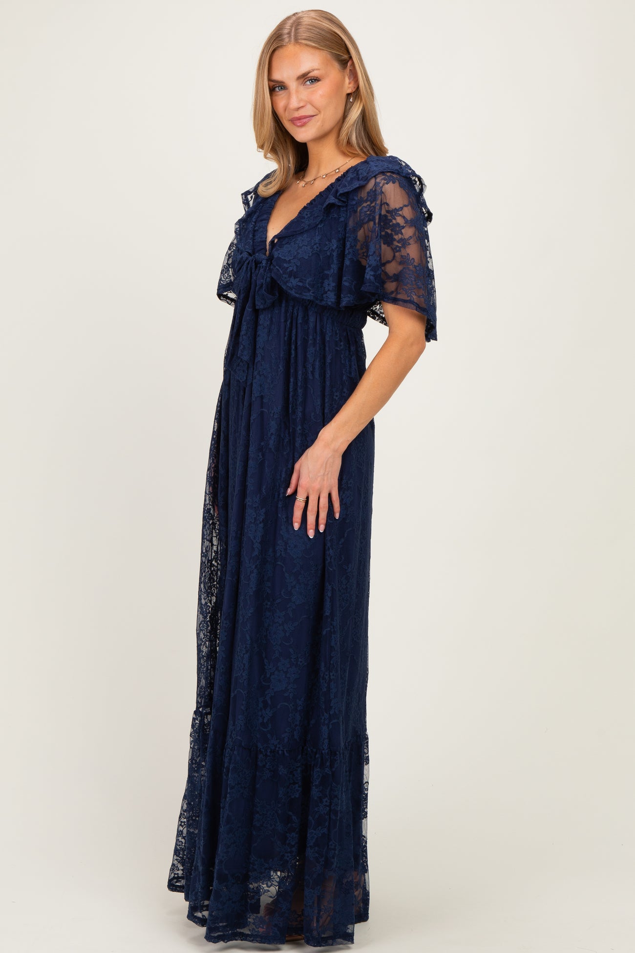 woman wearing a navy blue lace maxi dress with ruffle sleeves and a tie-front design