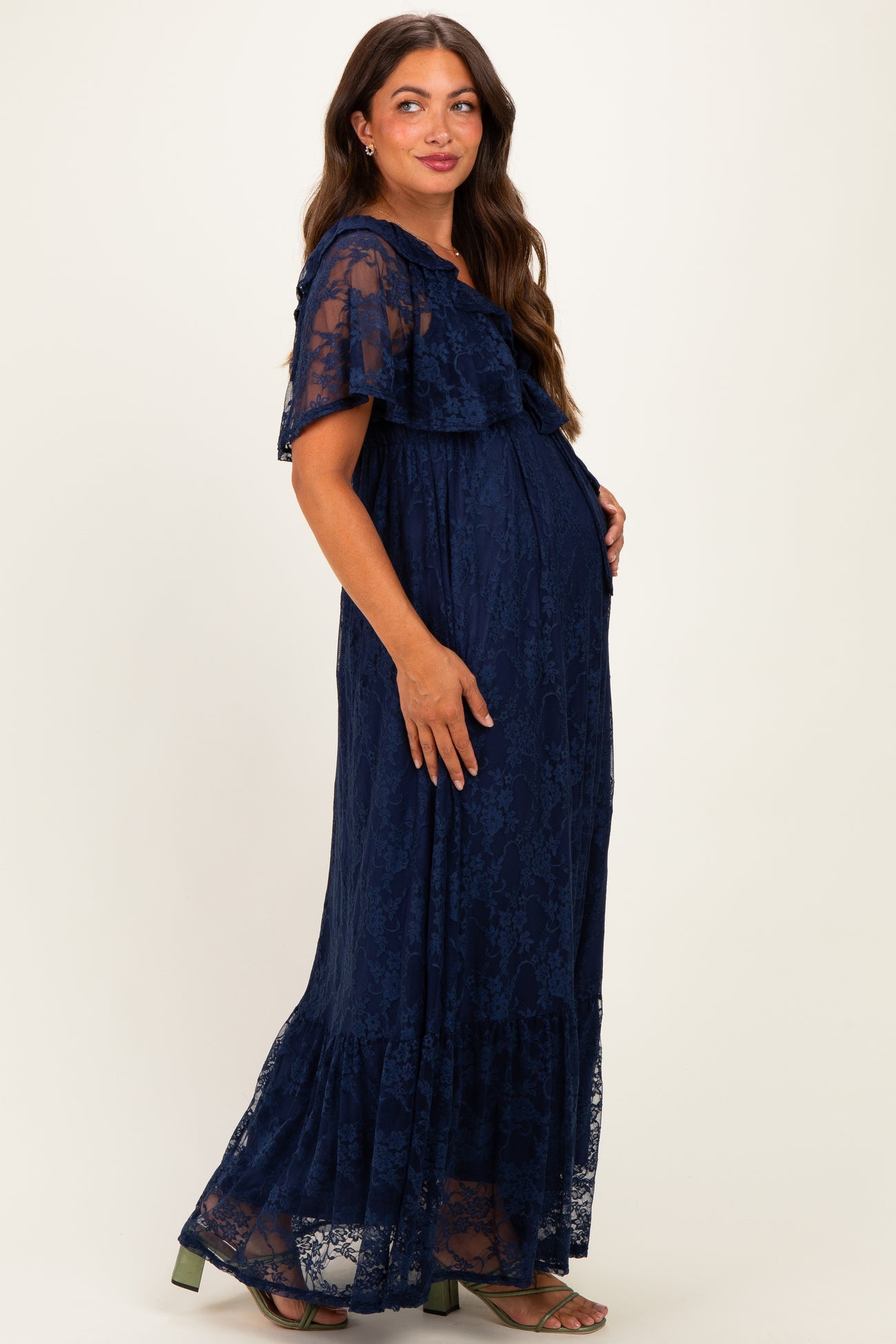 woman wearing a navy blue lace maternity maxi dress with ruffle sleeves and a visible baby bump