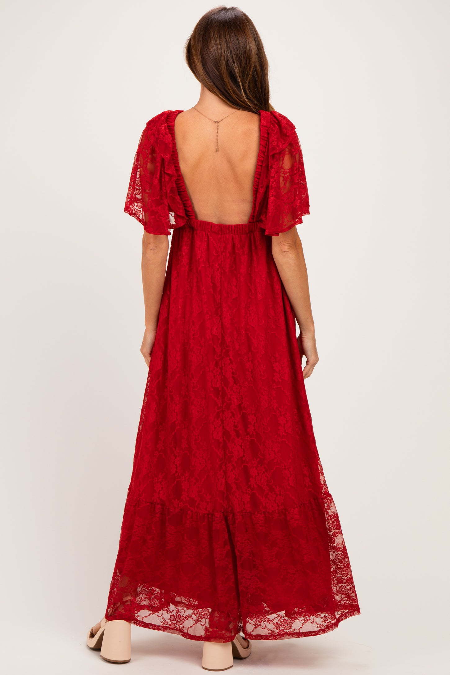 woman wearing a red lace maxi dress with short flutter sleeves and an open back detail
