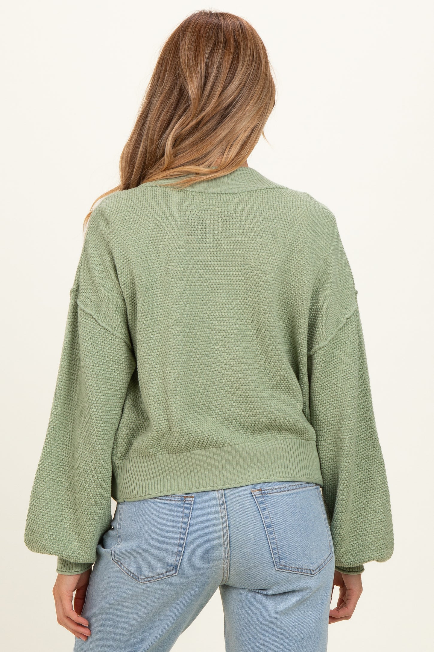 woman wearing a light green maternity sweater with balloon sleeves, shown from the back