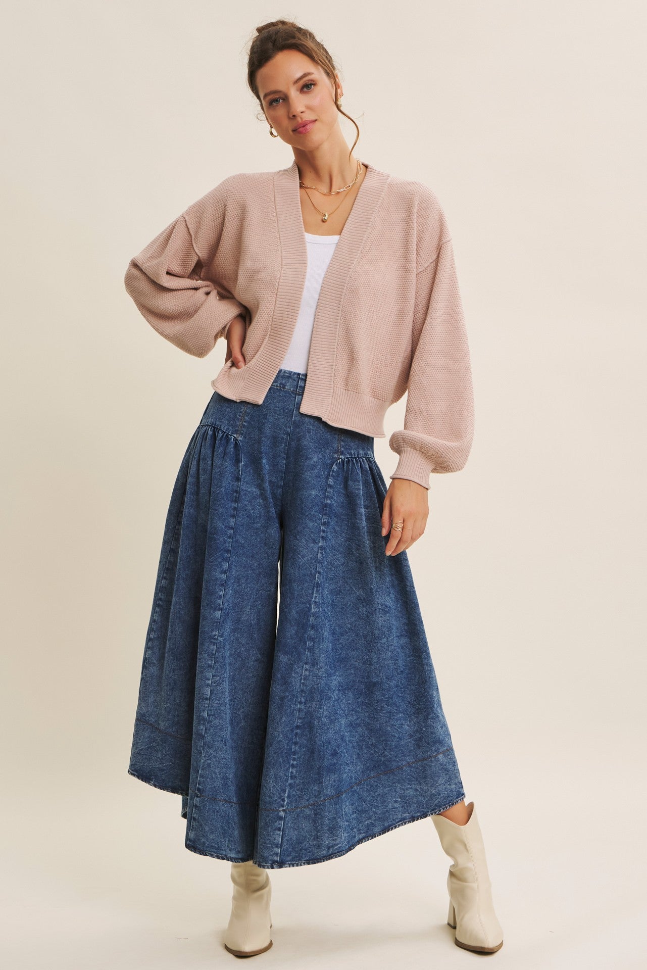 woman wearing a light pink oversized cardigan and a flowy denim skirt with pleats