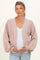 woman wearing a light pink maternity cardigan over a white top and holding her baby bump