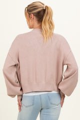 woman wearing a light pink cropped maternity cardigan with balloon sleeves, viewed from the back