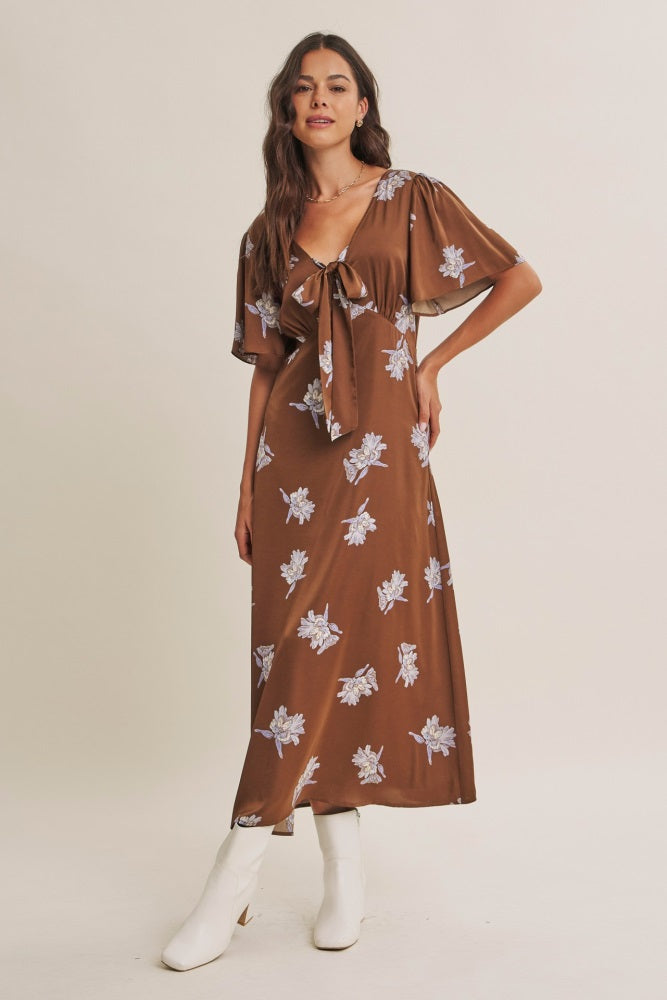 woman wearing a brown floral maxi dress with a tie front and flutter sleeves