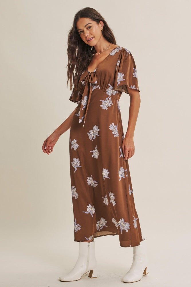 woman wearing a brown floral maxi dress with short sleeves and a tie front detail