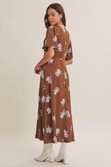 woman wearing a brown floral maxi dress with short sleeves and a flowy silhouette, standing in a side view