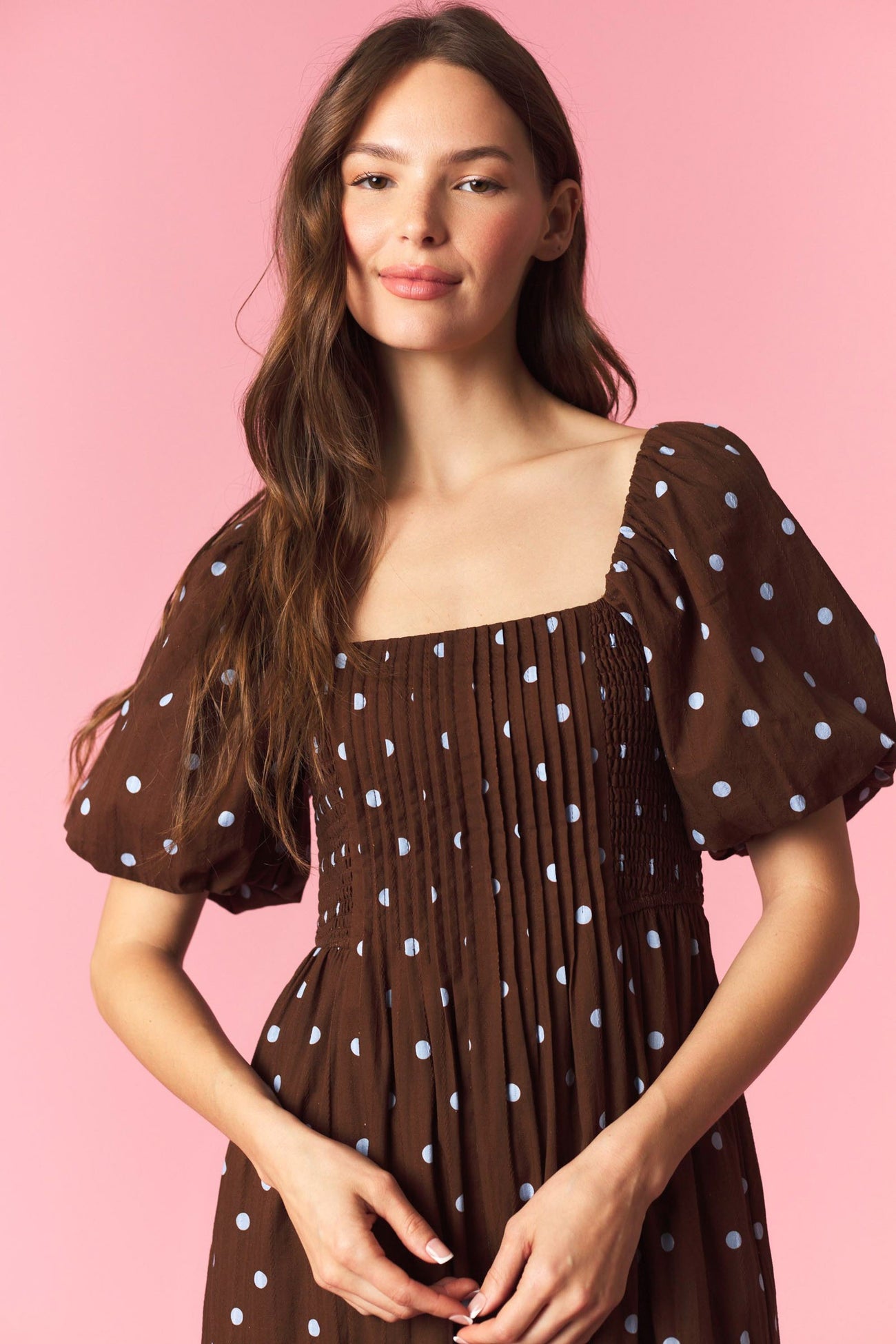 woman wearing a brown polka dot puff sleeve dress with a square neckline