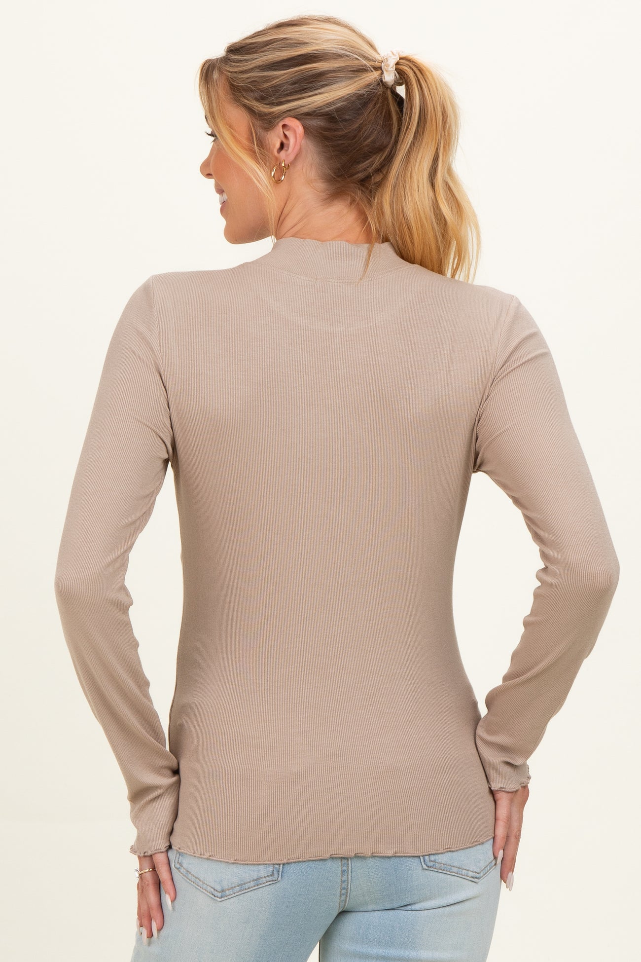 woman wearing a beige long sleeve maternity top, showing the back view with fitted ribbed details
