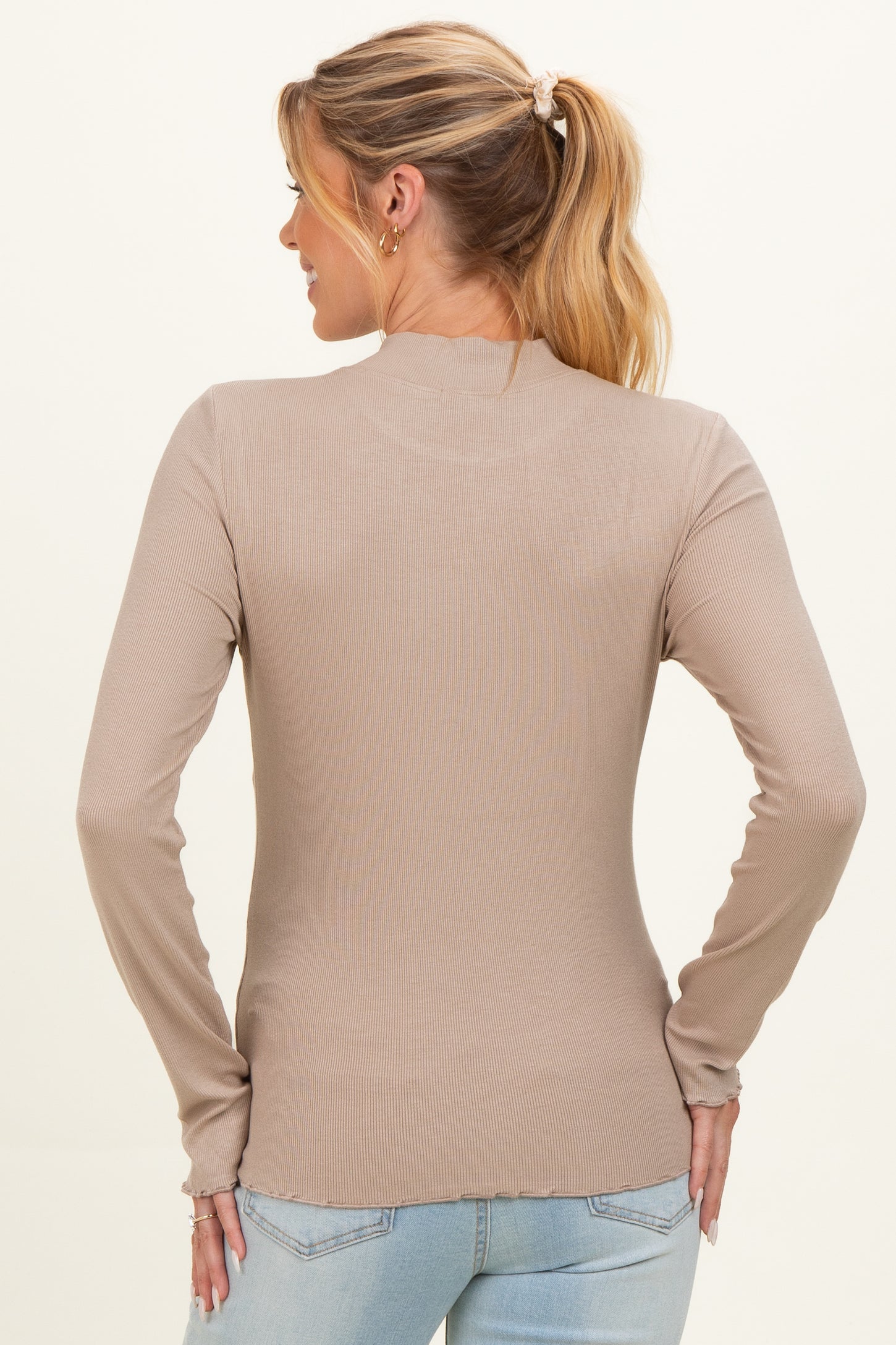 woman wearing a beige long sleeve maternity top, showing the back view with fitted ribbed details