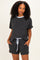woman wearing a grey short sleeve loungewear set with a blue trim and pockets in the shorts