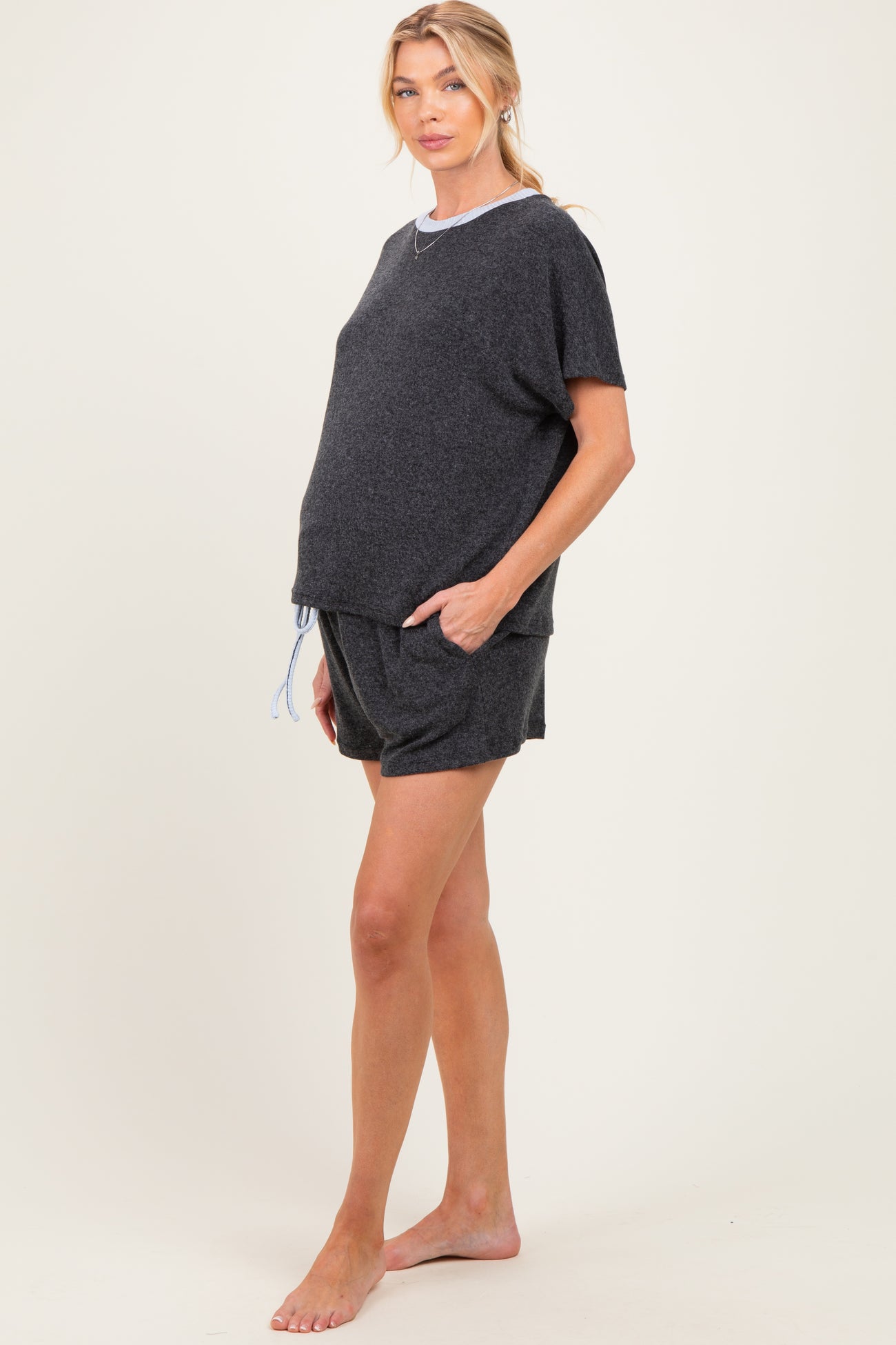 woman wearing a dark gray maternity loungewear set with a short sleeve top and matching shorts, showing baby bump