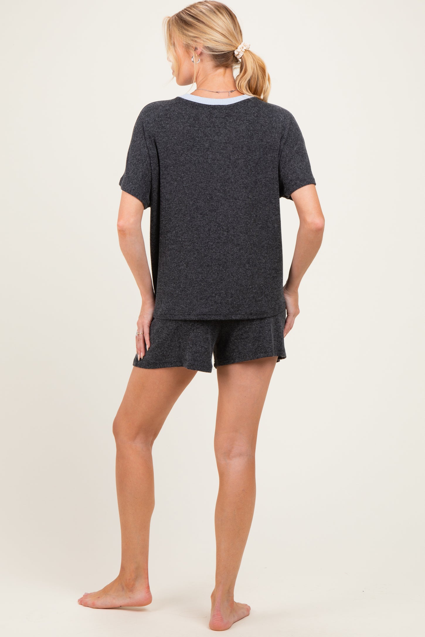 woman wearing a black maternity pajama set with a short sleeve top and shorts, showing a relaxed fit