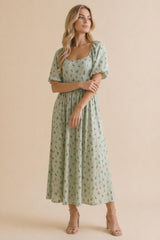 woman wearing a light green floral midi dress with puff sleeves and a square neckline, standing on a beige background