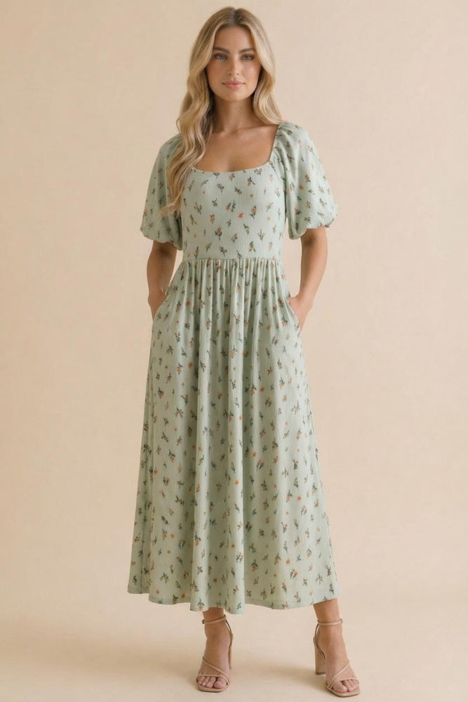 woman wearing a mint green puff sleeve midi dress with floral prints and pockets, styled with strappy heels