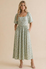 woman wearing a mint green puff sleeve midi dress with floral prints and pockets, styled with strappy heels