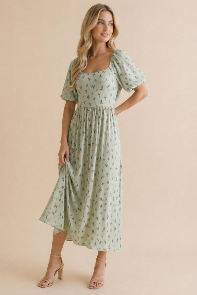 woman wearing a green floral midi dress with puff sleeves and a square neckline