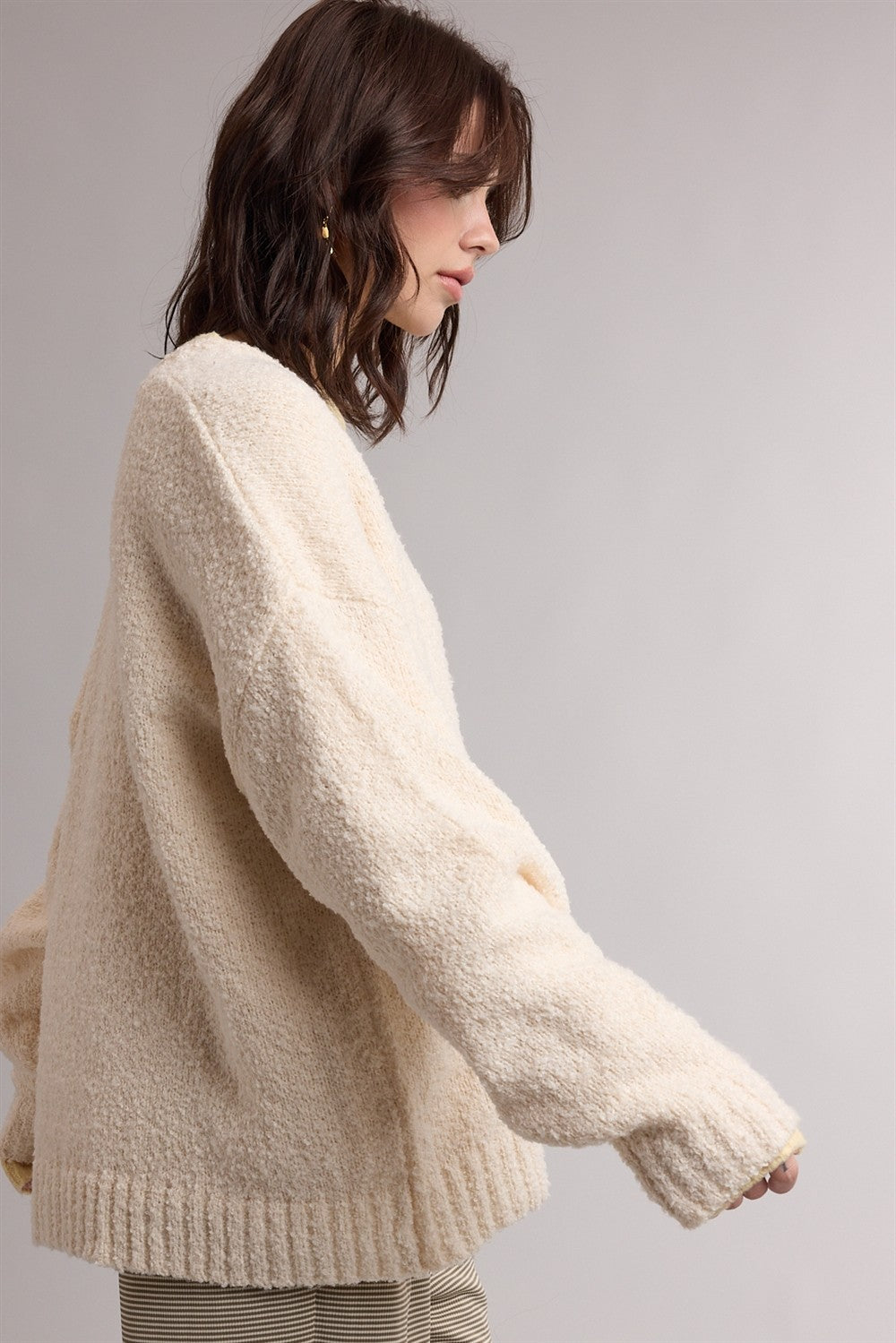 woman wearing a cream oversized fuzzy sweater with long sleeves and a relaxed fit