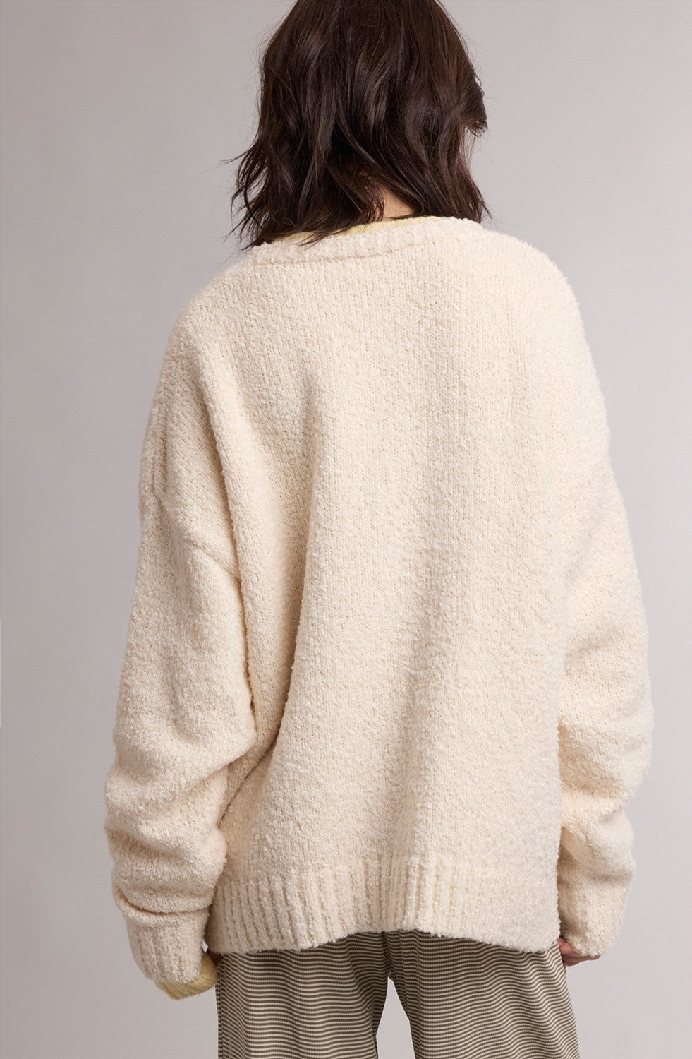 woman wearing a cozy cream-colored oversized sweater, viewed from the back, with relaxed fit and textured fabric