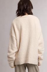 woman wearing a cozy cream-colored oversized sweater, viewed from the back, with relaxed fit and textured fabric