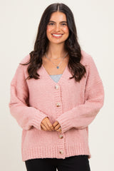 woman wearing a pink fluffy cardigan with buttons and a v-neckline, styled with a grey top underneath and black pants