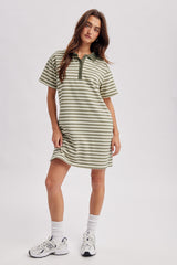 woman wearing a green and white striped polo dress with a collar and short sleeves, styled with white sneakers