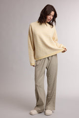 woman wearing a light yellow striped oversized sweater and beige wide-leg pants, standing in a relaxed pose