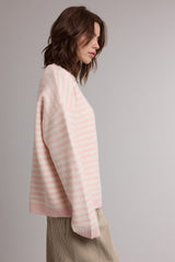 woman wearing a pastel pink and white striped oversized sweater with a relaxed fit