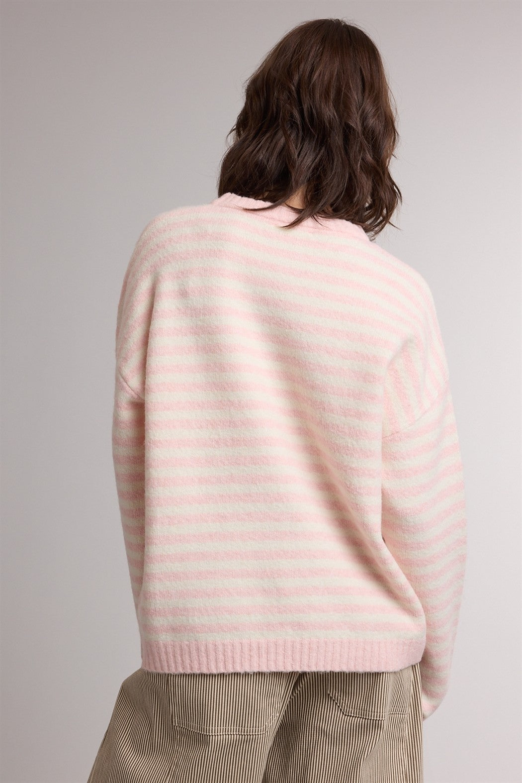 woman wearing a light pink and white striped oversized sweater, viewed from the back