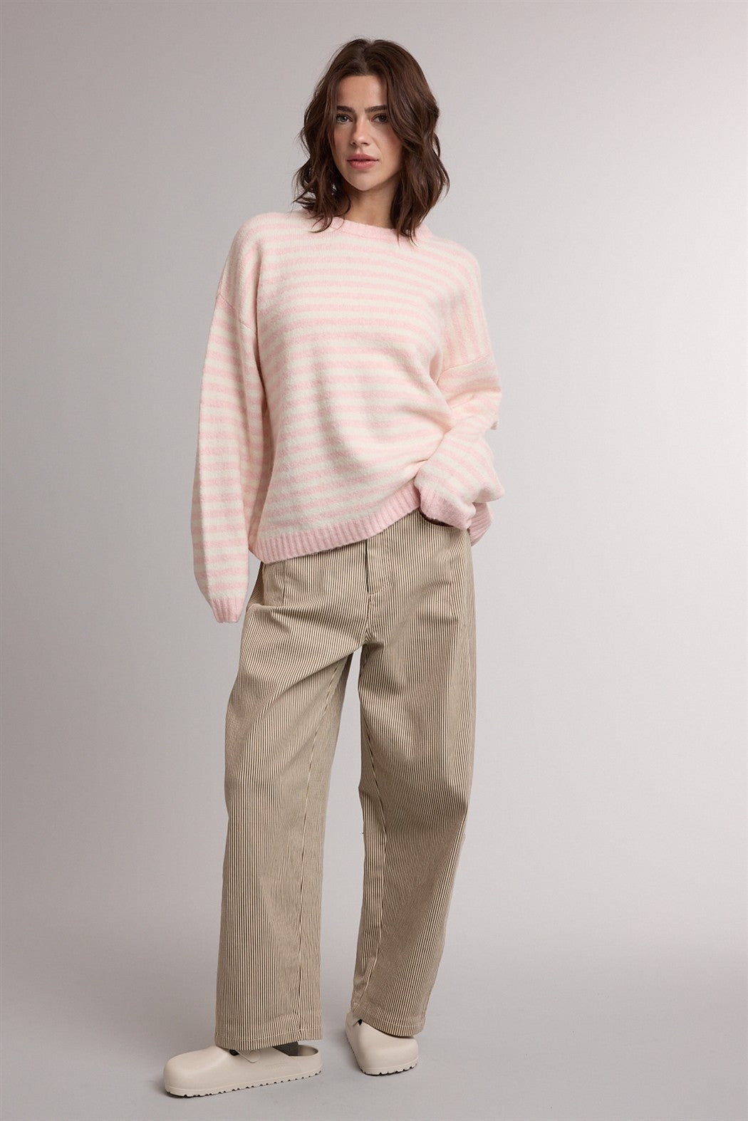 woman wearing a light pink striped sweater and beige corduroy wide-leg pants