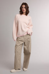 woman wearing a light pink striped sweater and beige corduroy wide-leg pants
