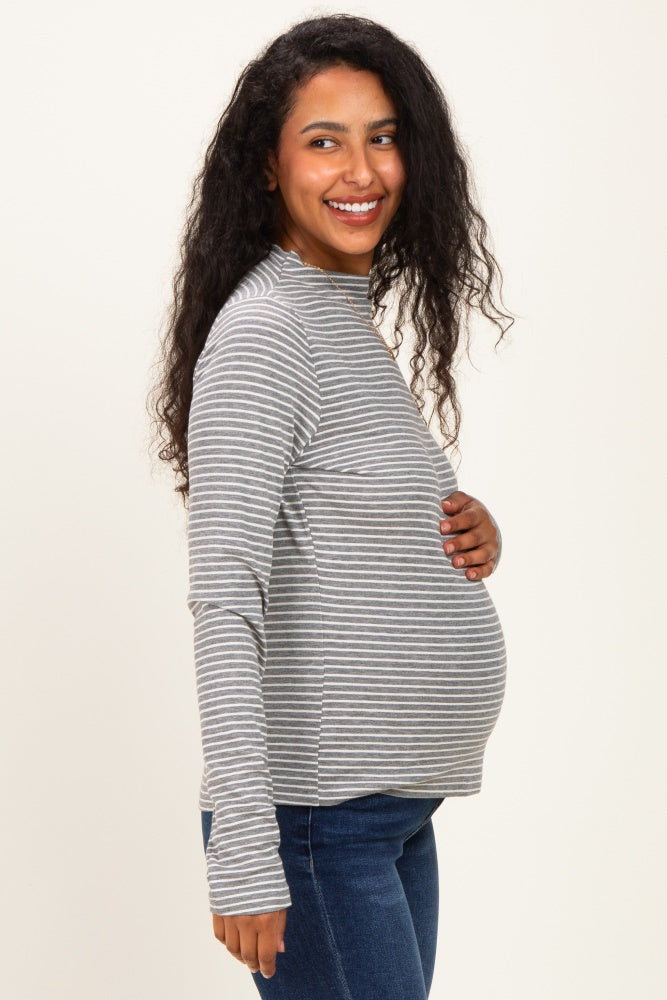woman wearing a gray and white striped maternity long sleeve top and holding her baby bump